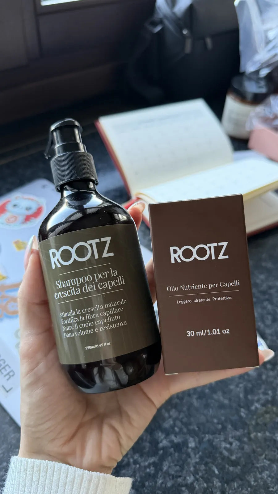 Una clienta sostiene el bote del champú y la caja del aceite ROOTZ recién abiertos